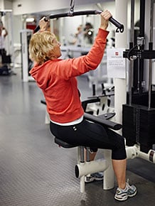 Bild på kvinna som tränar på gym. Illustrerar friskvård.